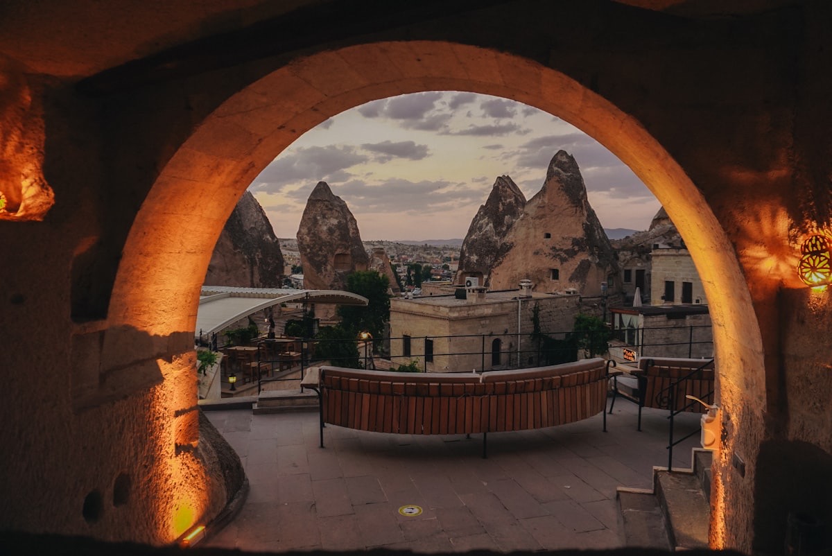 A cave terrace framed by a stone archway looking out over the fairy chimneys of Cappadocia at golden hour
