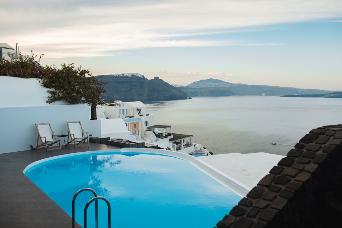 A private infinity pool overlooking the sea and whitewashed buildings at dusk
