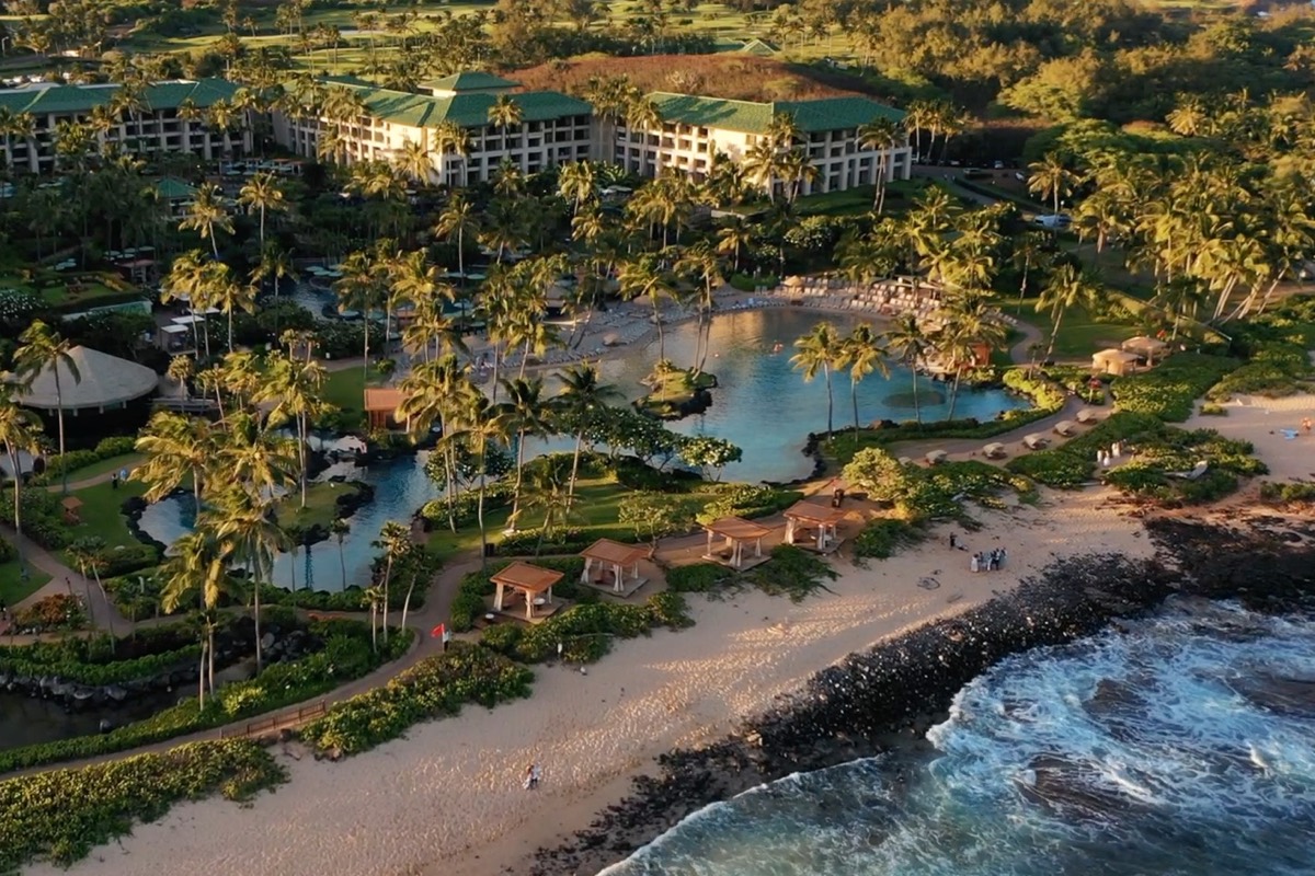 Aerial view of the Grand Hyatt Kauai lagoon pool and resort grounds at golden hour