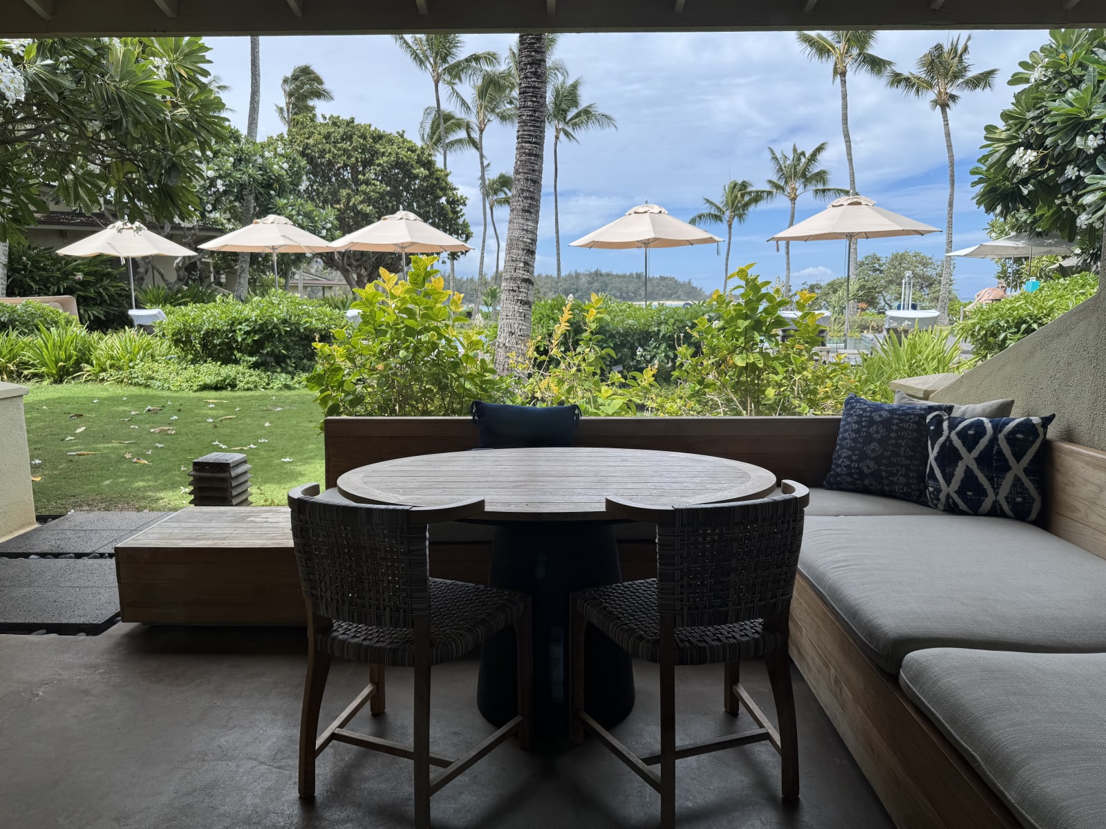 The private outdoor lanai and dining area of an Ocean Bungalow, shaded by palm trees