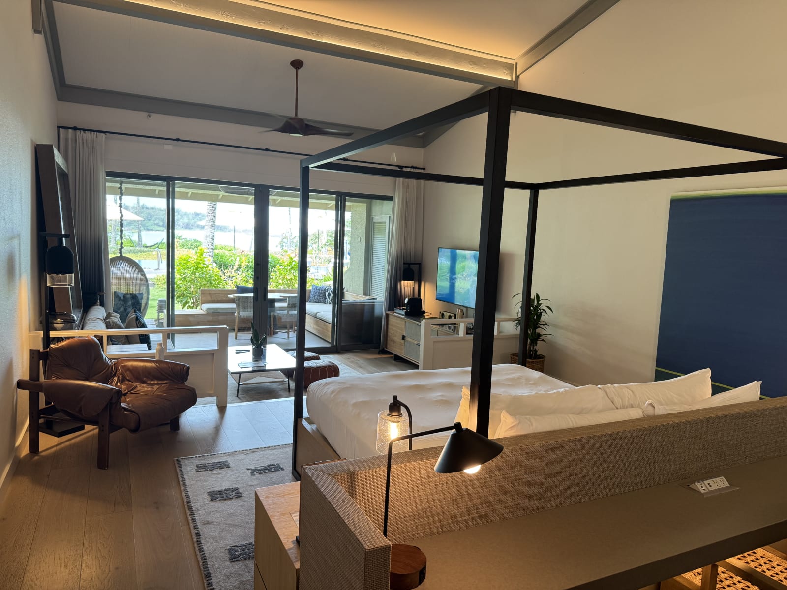 A king bungalow bedroom at The Ritz-Carlton O'ahu, Turtle Bay with a canopy bed and glass doors opening to the ocean