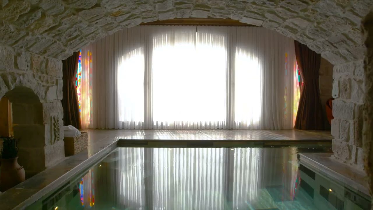 The Muhtesem cave pool suite at Museum Hotel: a private pool under a stone arch with stained glass windows
